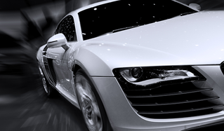 Coche deportivo plateado a gran velocidad; vista frontal, fondo desenfocado.