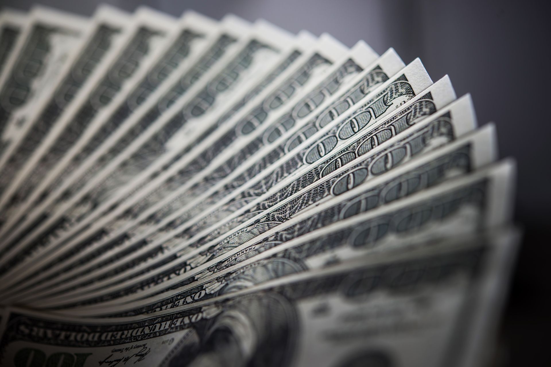 Fan of hundred-dollar bills, angled, with details visible.