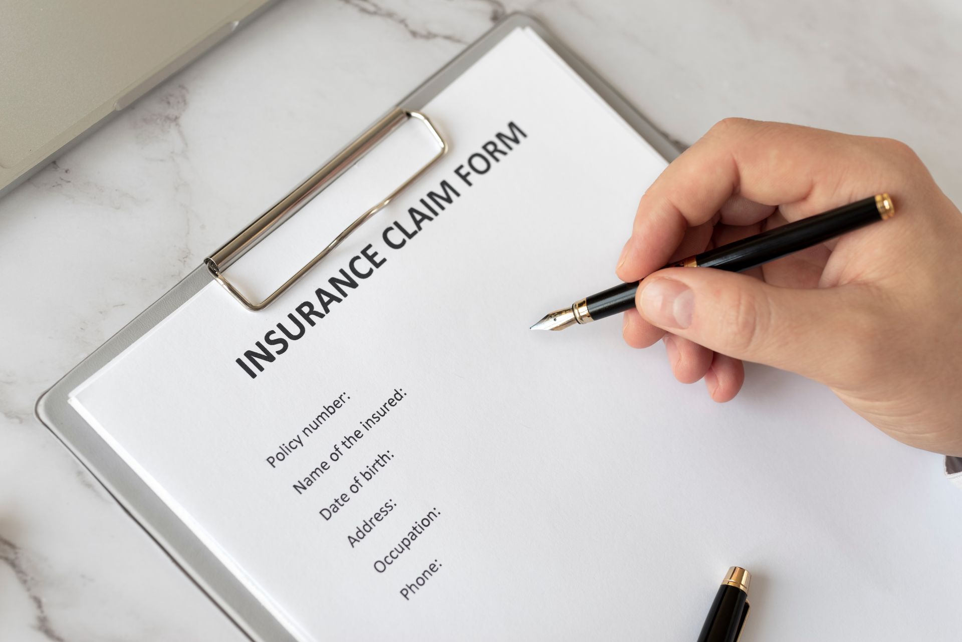 Insurance Claim Form Close Up Hand Holding Pen To A Insurance Claim Form