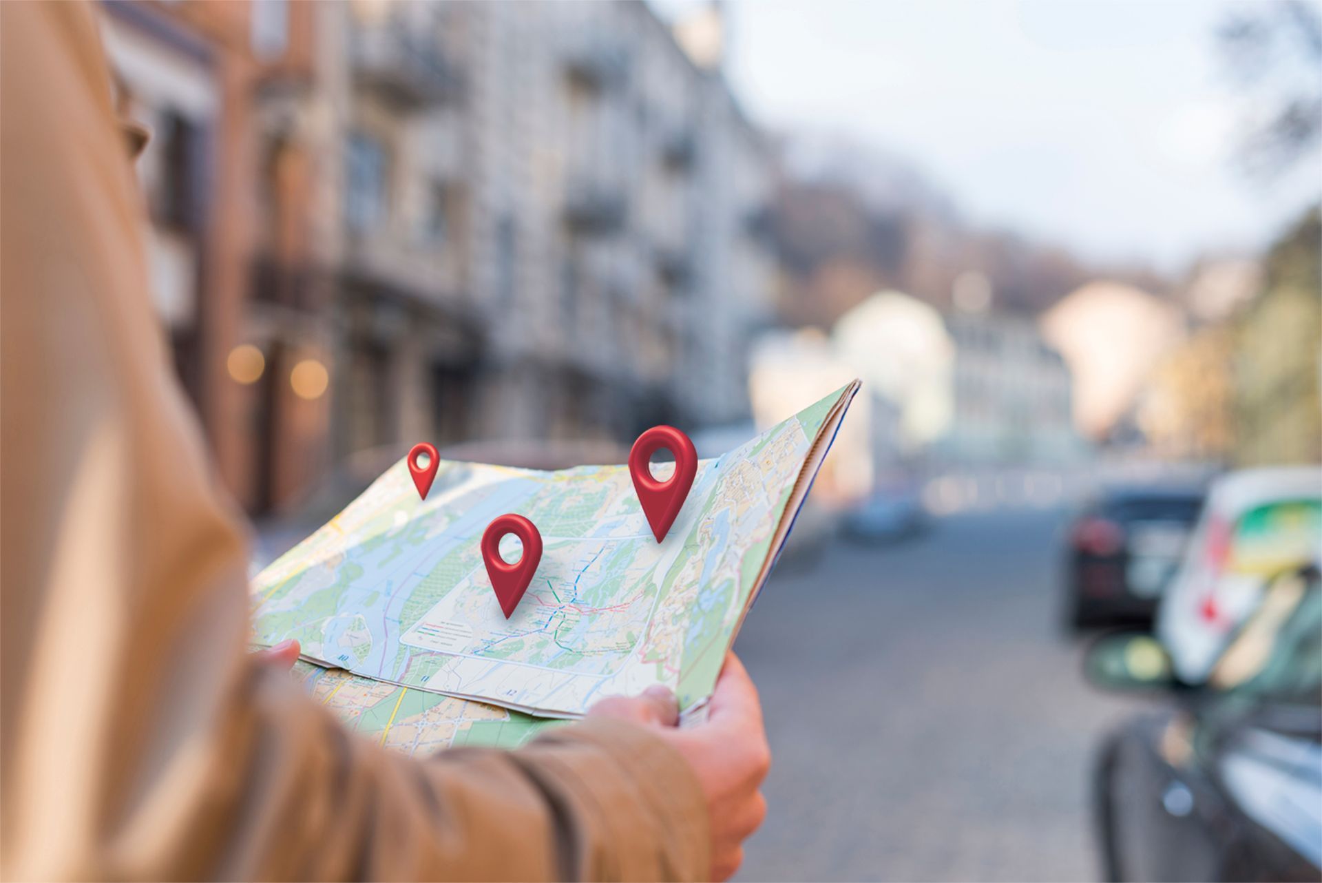 Person holding map with three red location markers on city street.