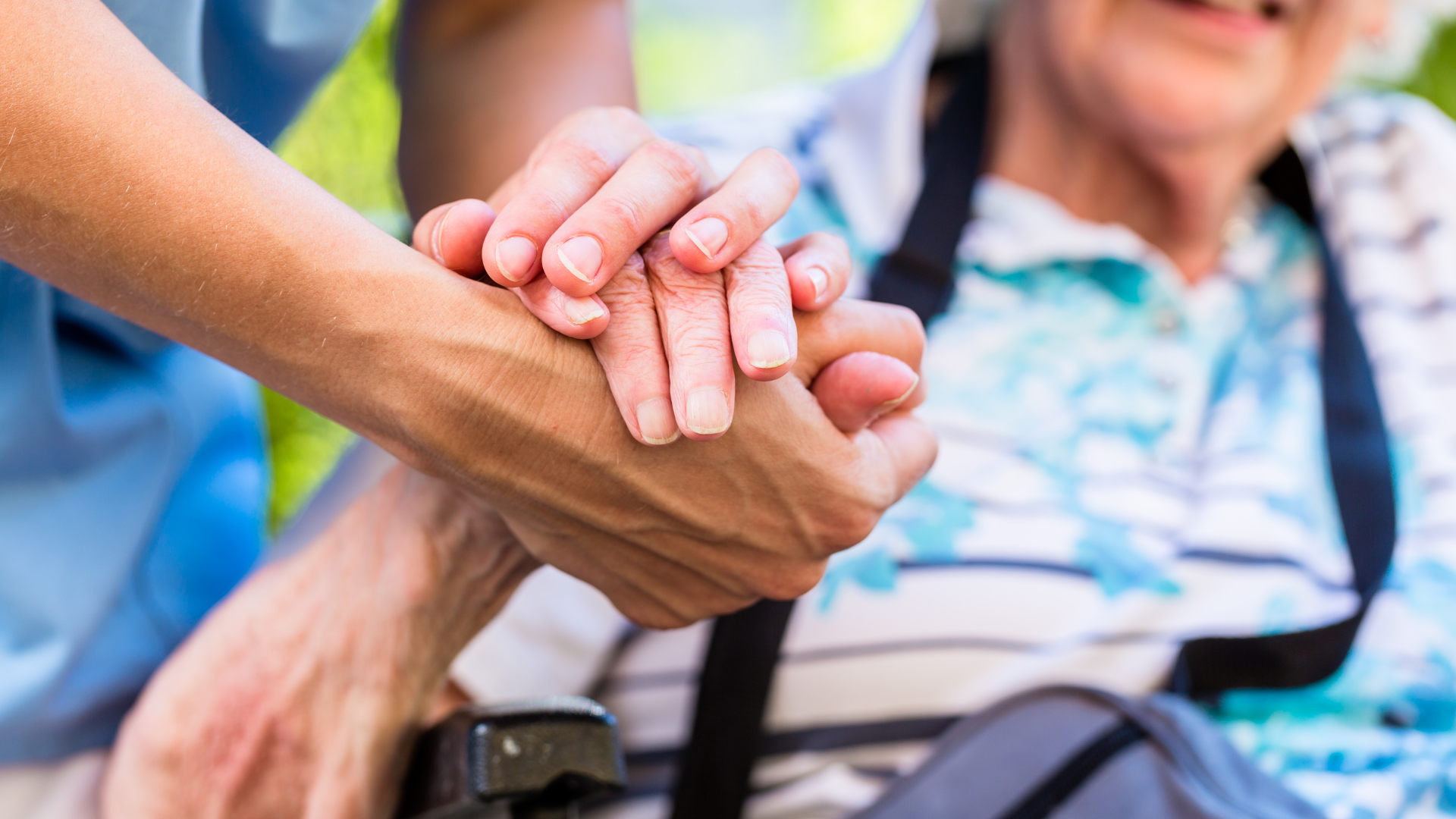 a nurse is holding the hand of an elderly woman in a wheelchair .