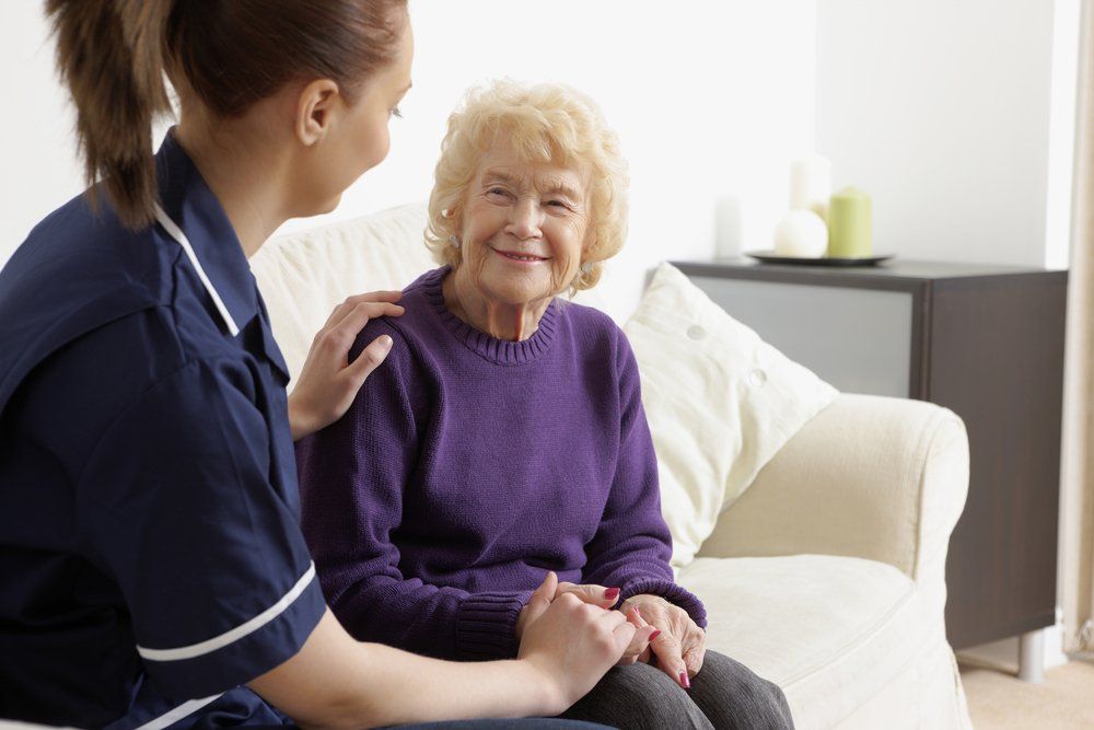 a nurse is talking to an elderly woman who is sitting on a couch .