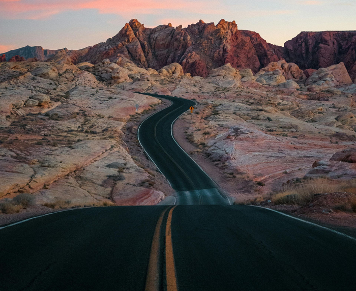 winding asphalt road through the Nevada desert at sunset