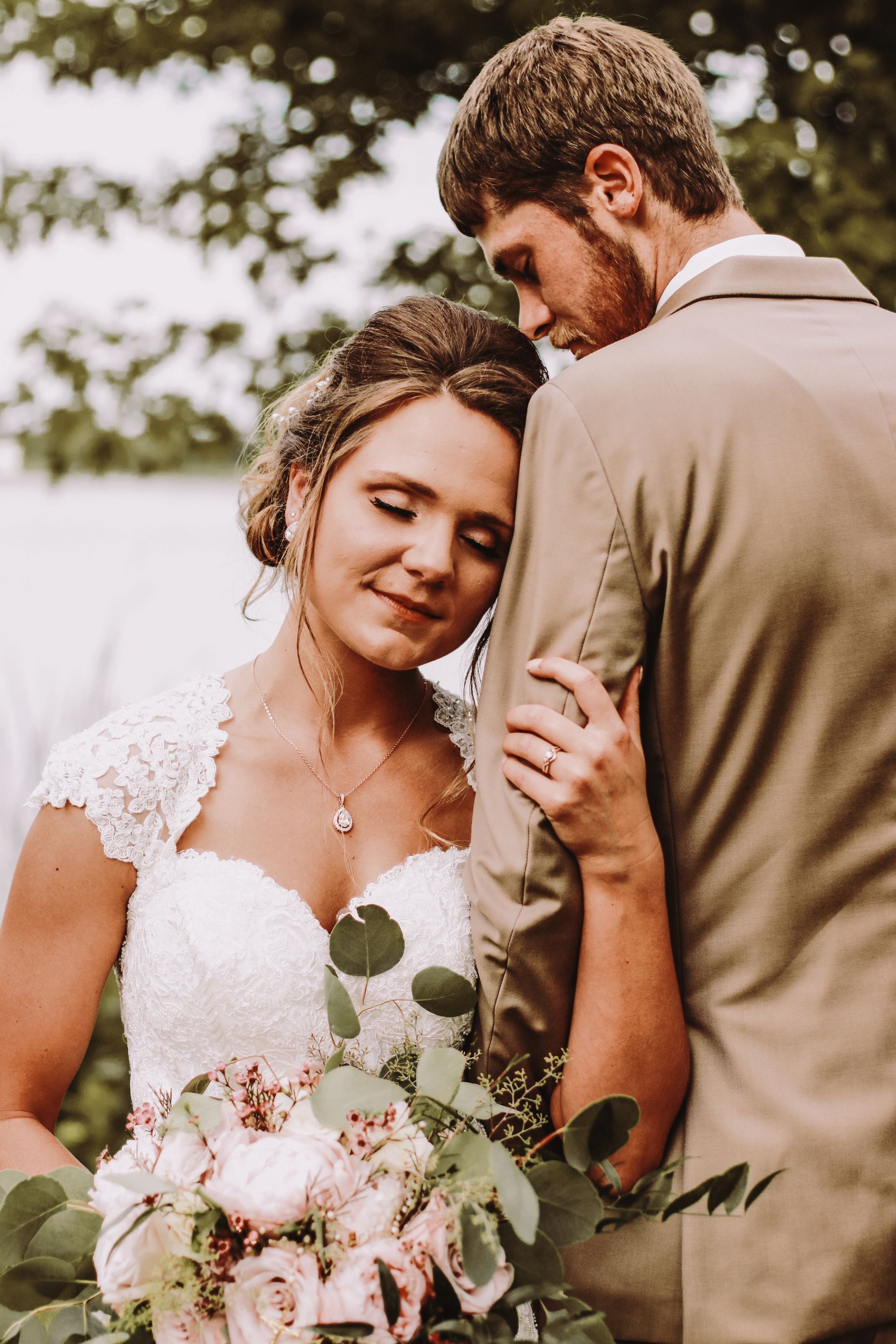 A man and a pregnant woman are kissing in a park.