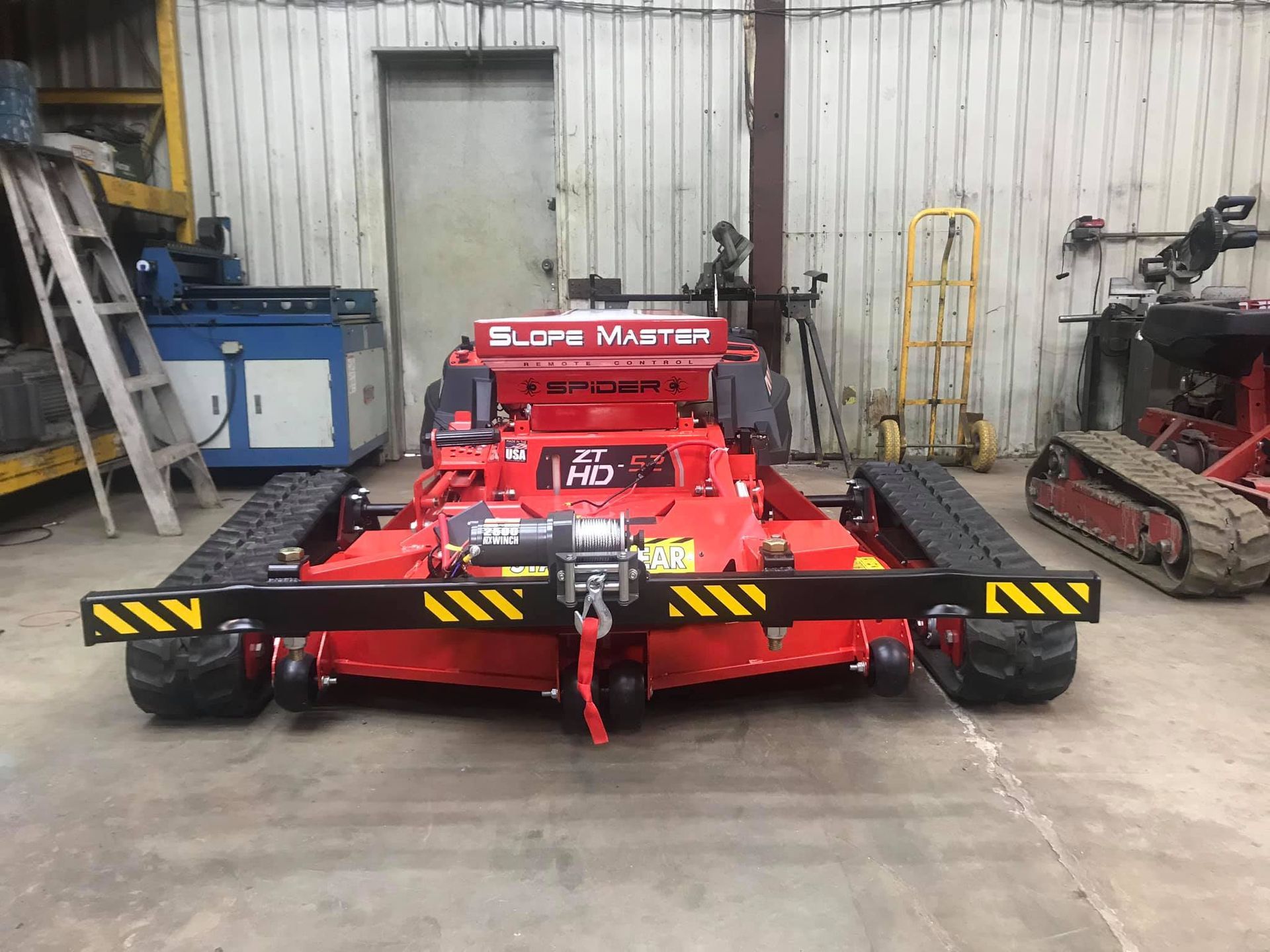Red Slope Master mower with tracks, in a garage.