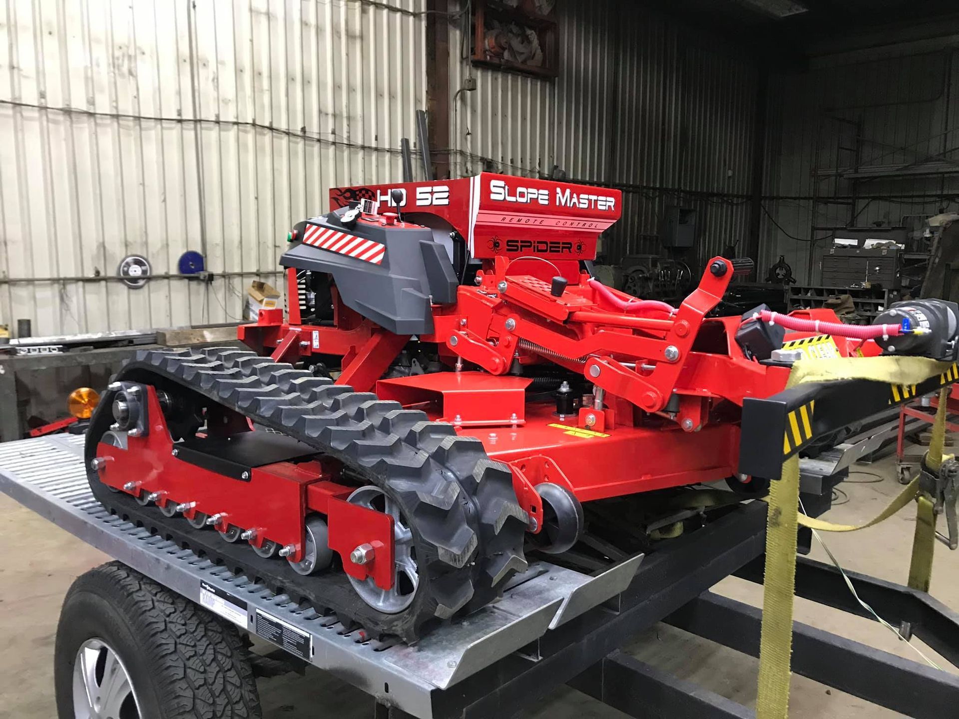Red Slope Master machine on a trailer, designed for terrain work, with a black tire track system.