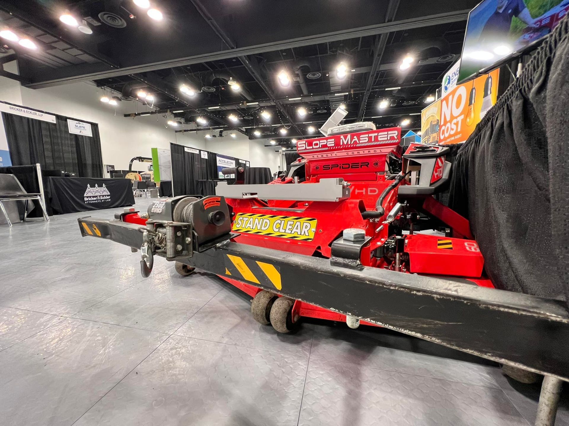 Red and black industrial machine on wheels, possibly for construction, at an exhibition hall.