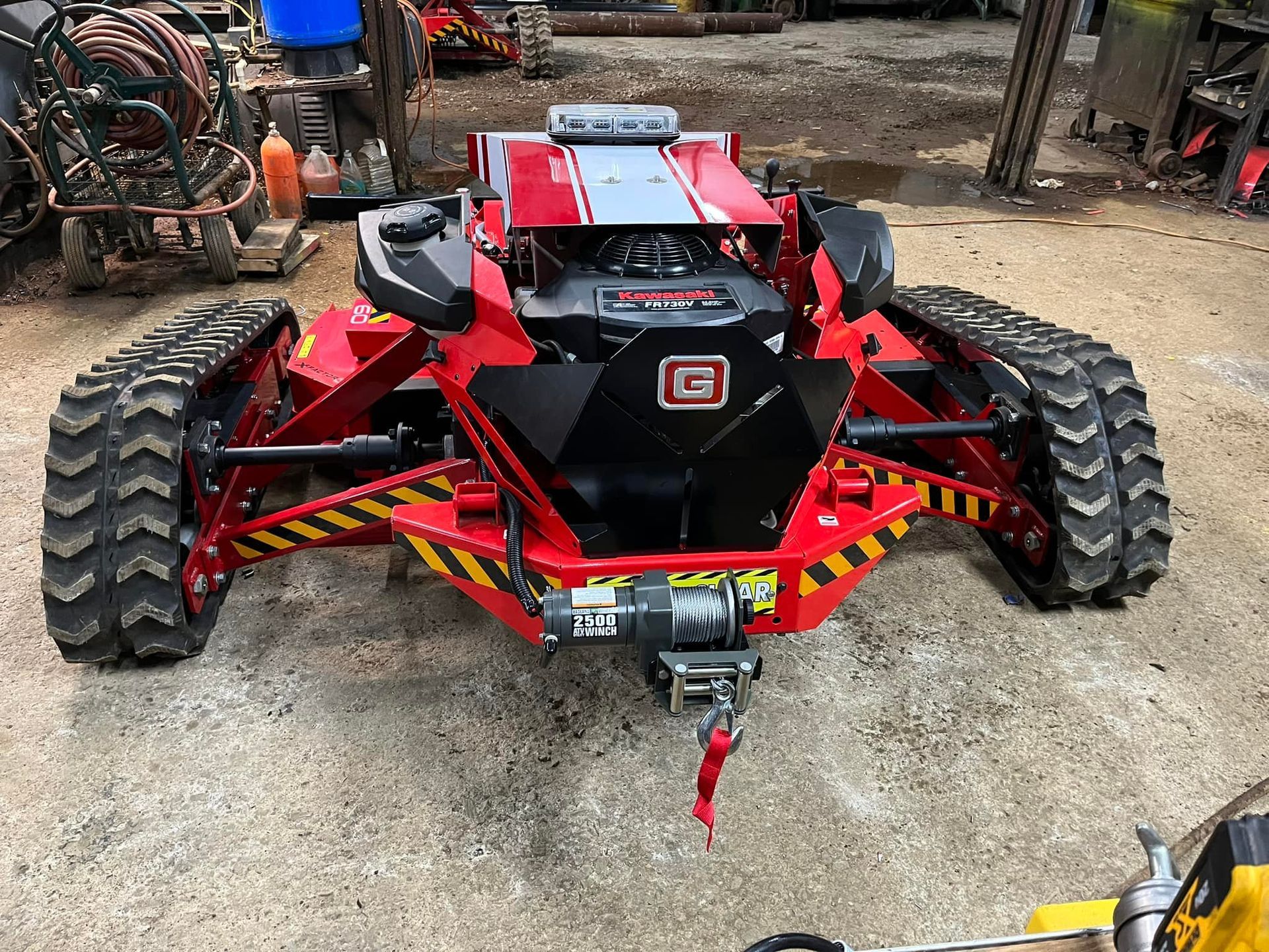 Red and black tracked vehicle with winch, indoors.