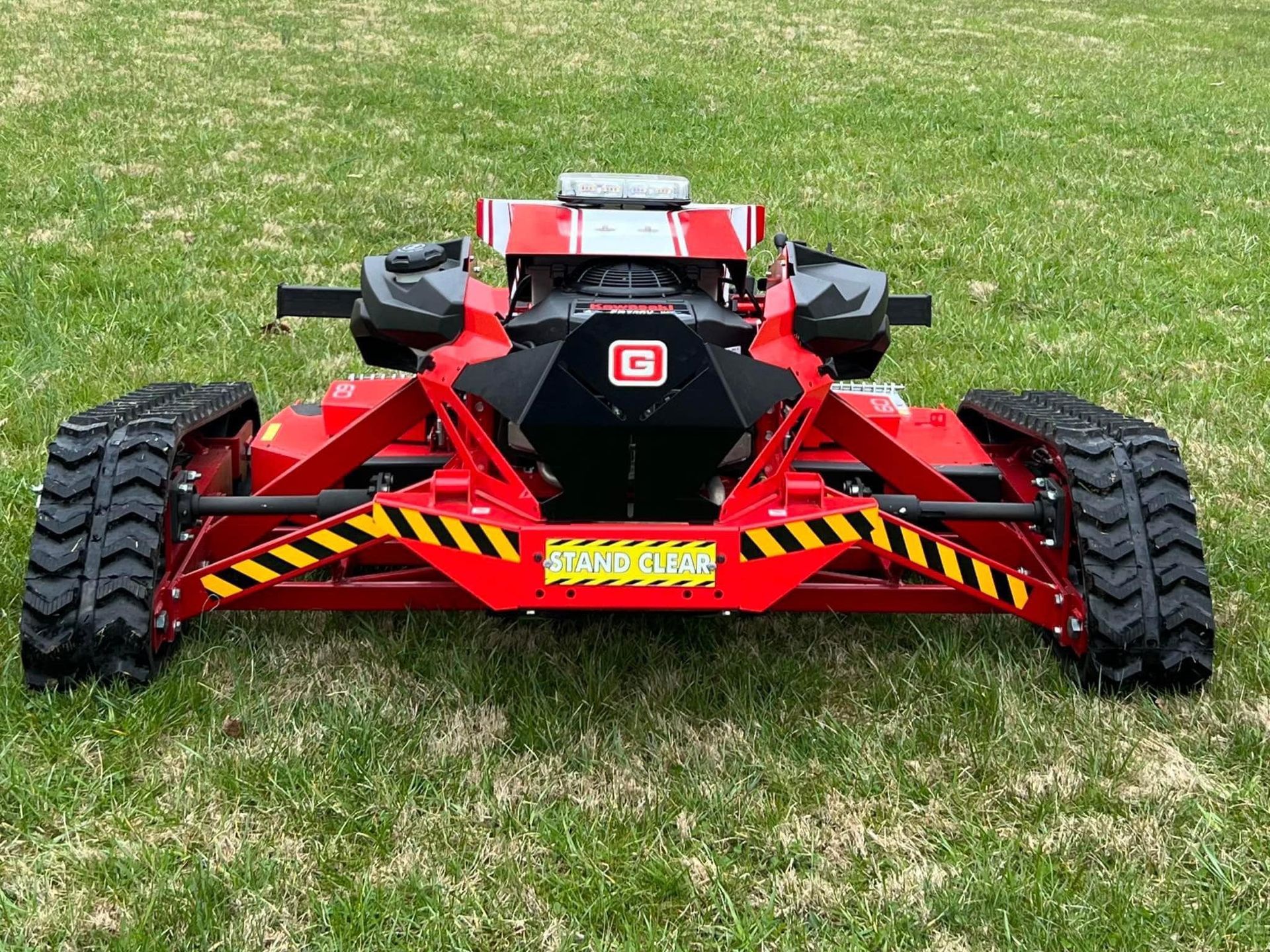 Red and black tracked mower on grass.