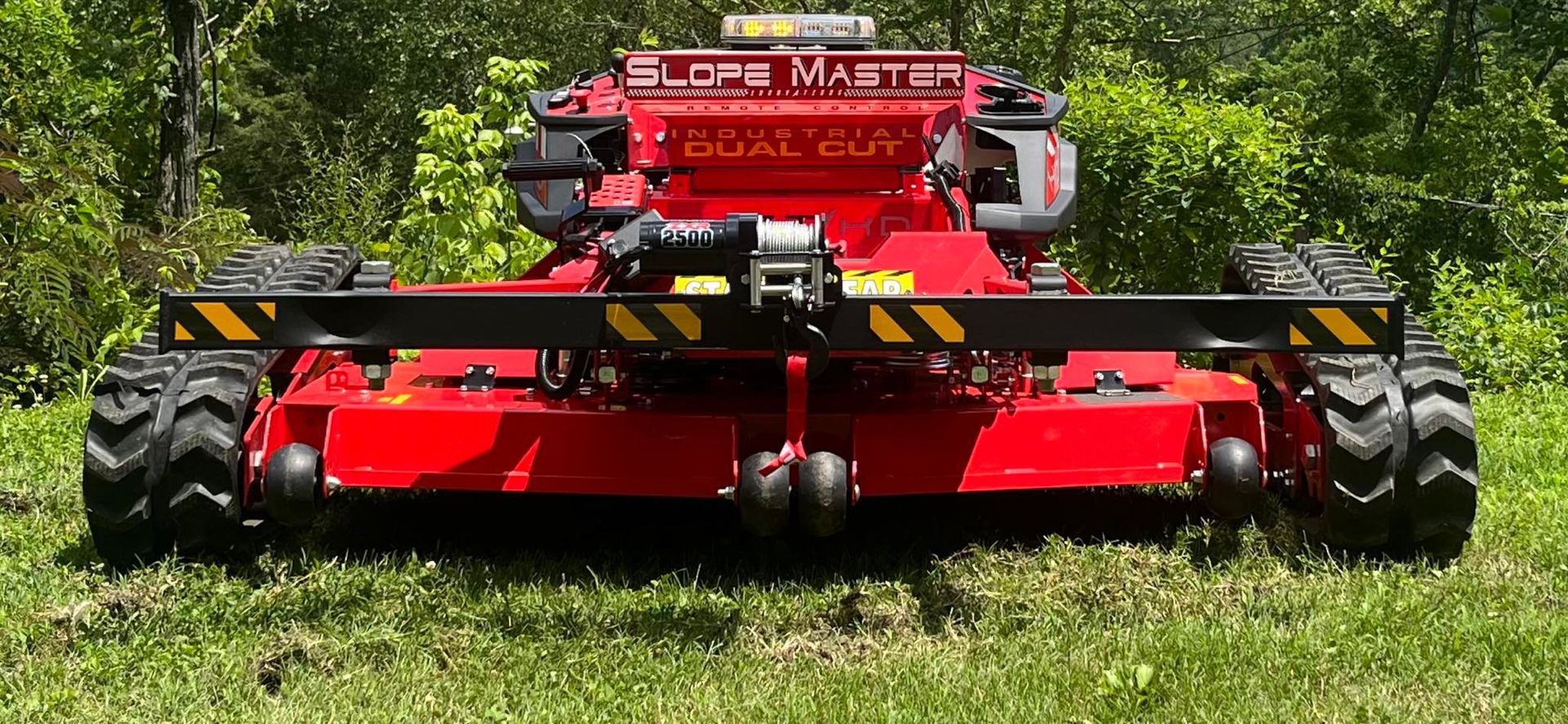 Red Slope Master mower on green grass with trees in the background.