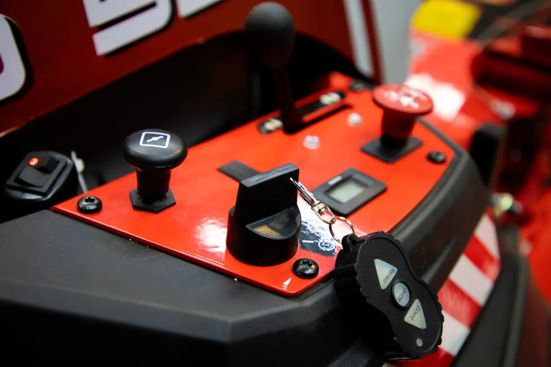 Red control panel on a machine with black knobs, a lever, and a remote control.