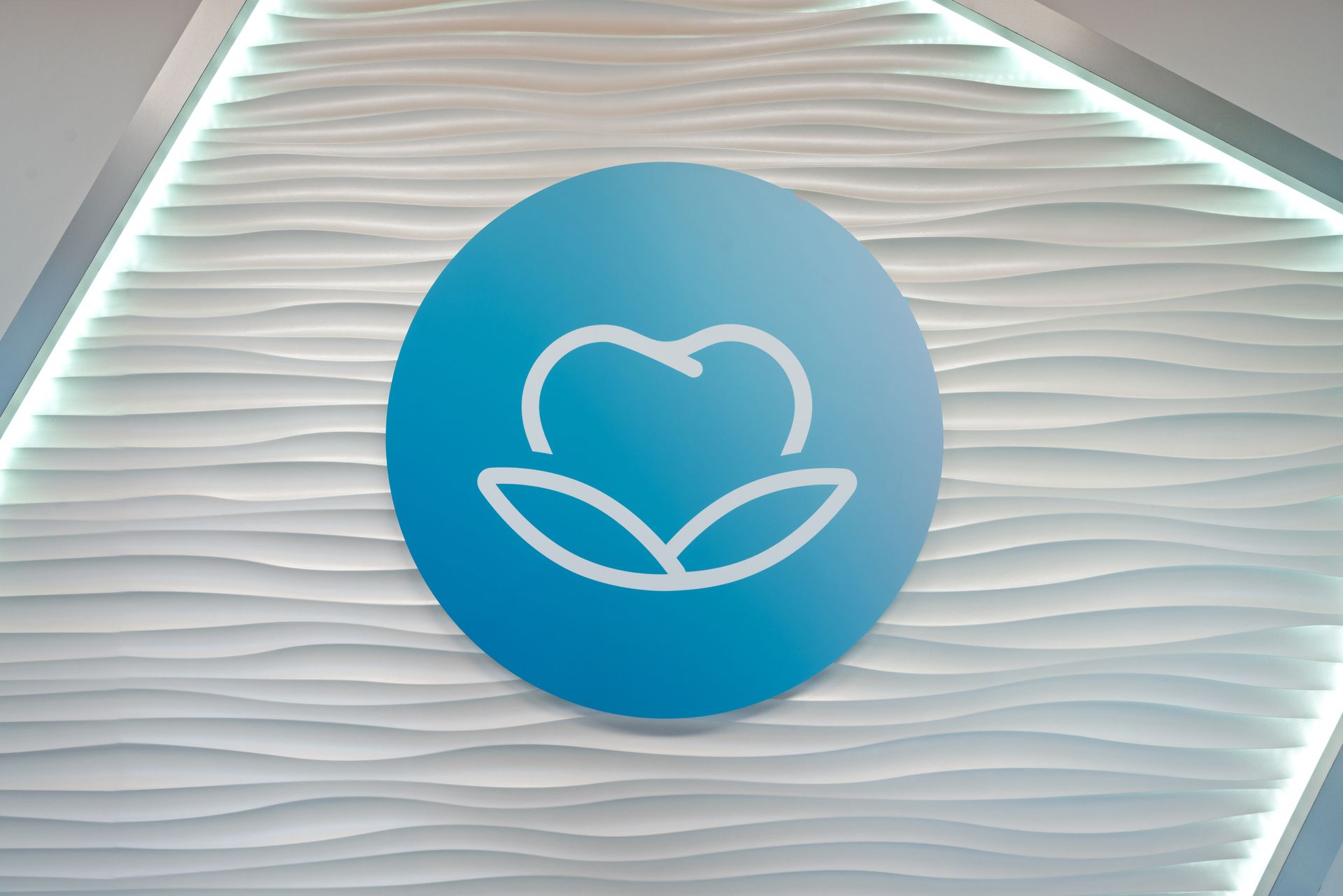 A blue circle with a heart and leaves inside of it on a white wall.