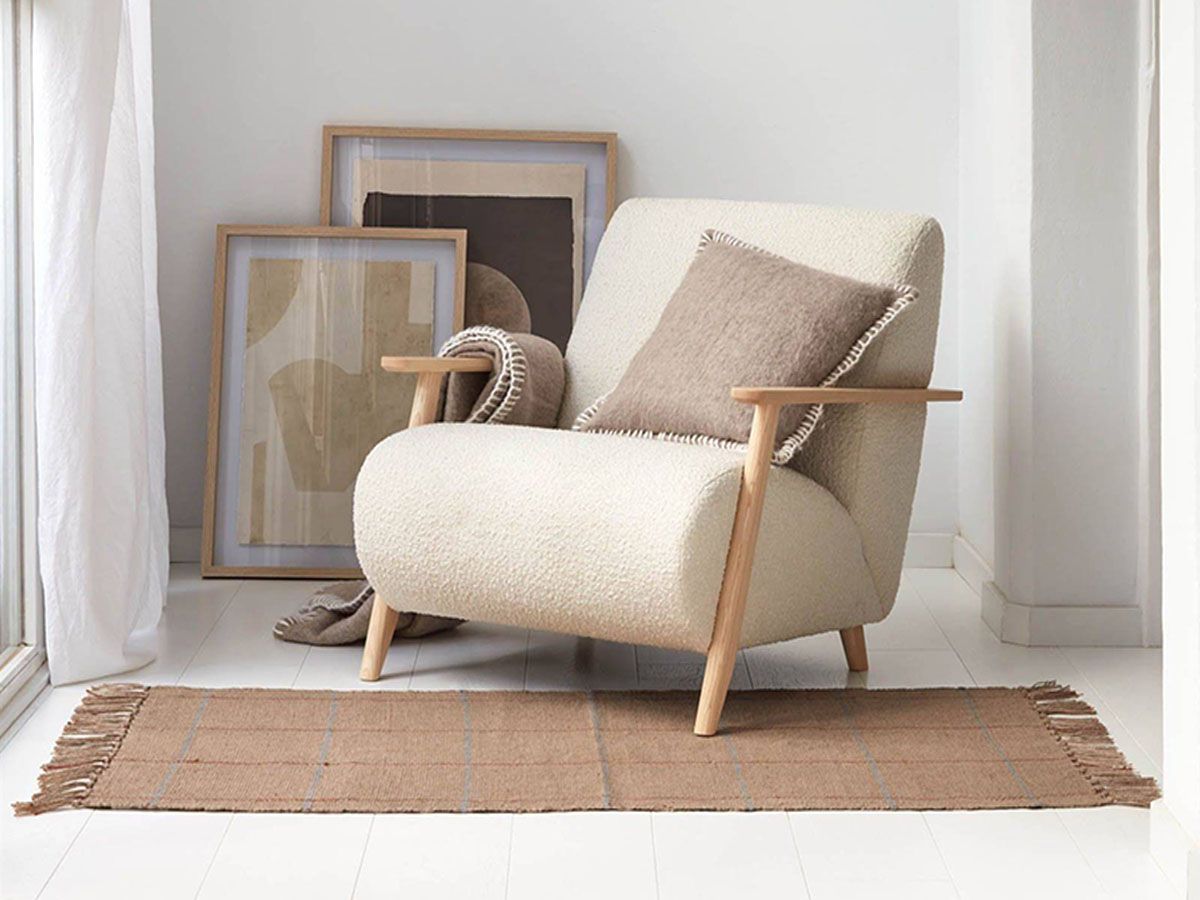 una silla blanca está sentada en una habitación junto a una alfombra marrón