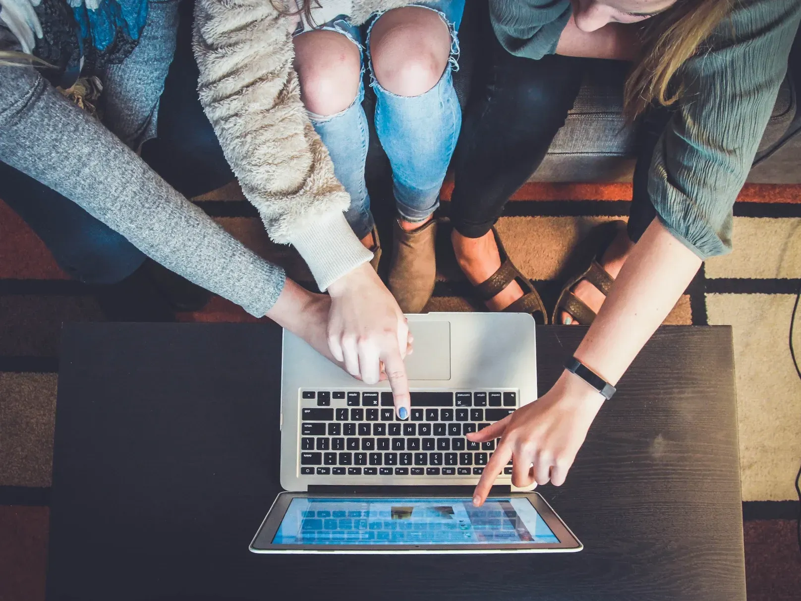 Three women are sitting on a couch looking at a laptop computer.