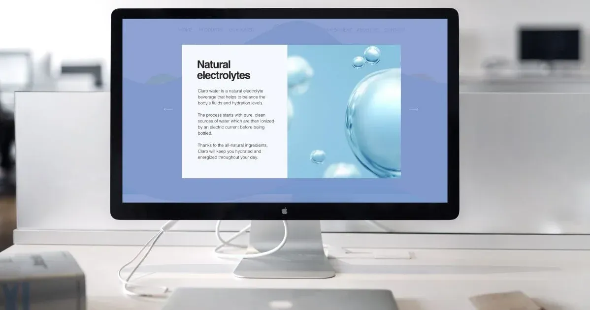 A computer monitor is sitting on a desk with a  website about water bottles on screen. Water company
