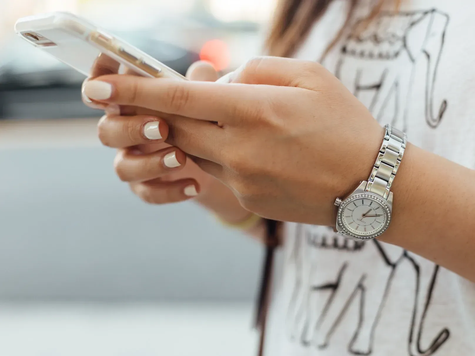 A woman wearing a watch is using a cell phone.To