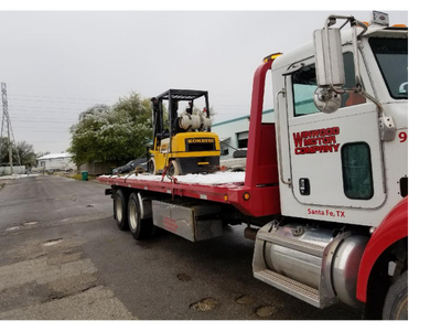 Yellow forklift on a flatbed truck; snowy scene; Western Water Company truck, Santa Fe, TX.