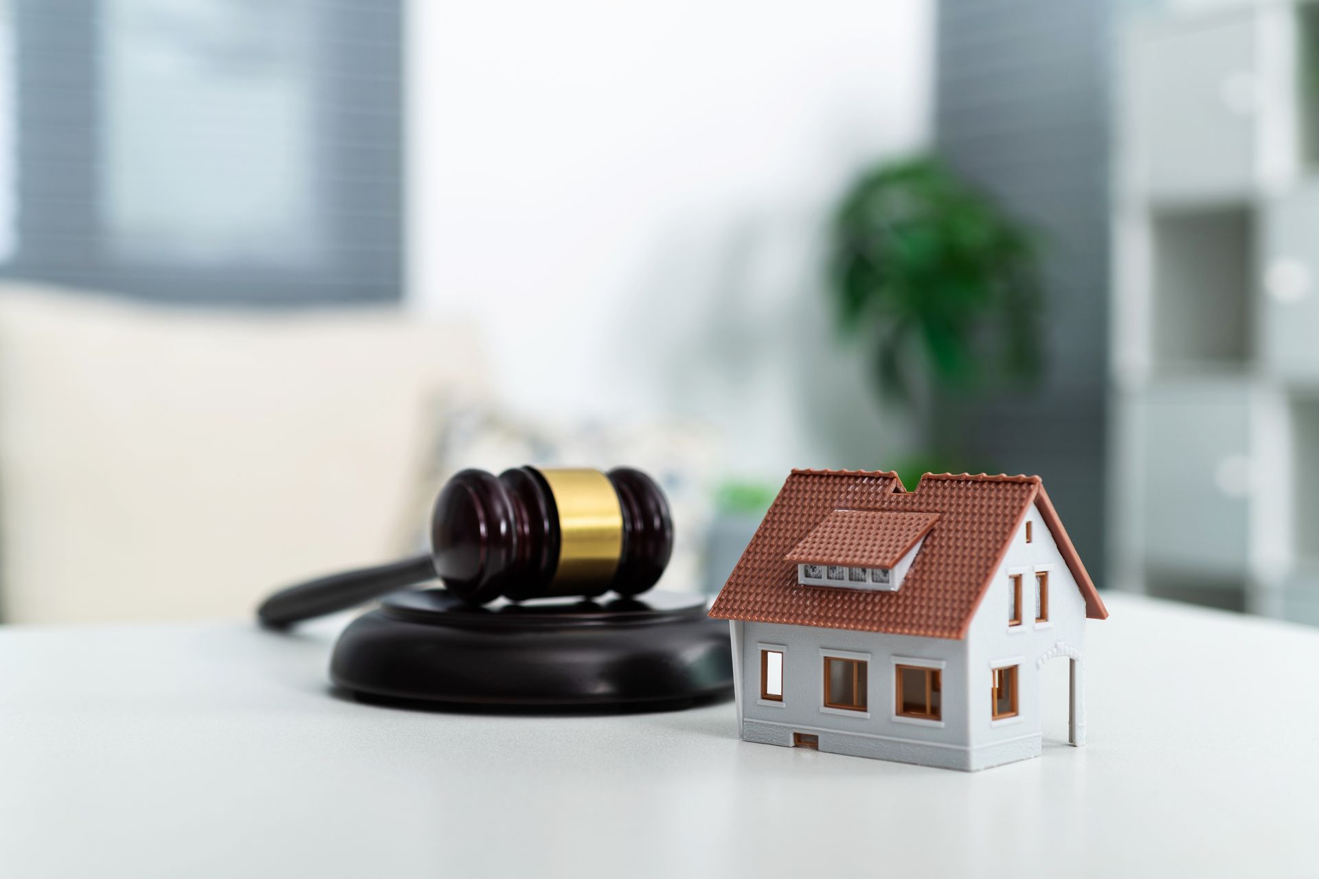 A small model house is sitting next to a judge 's gavel on a table.
