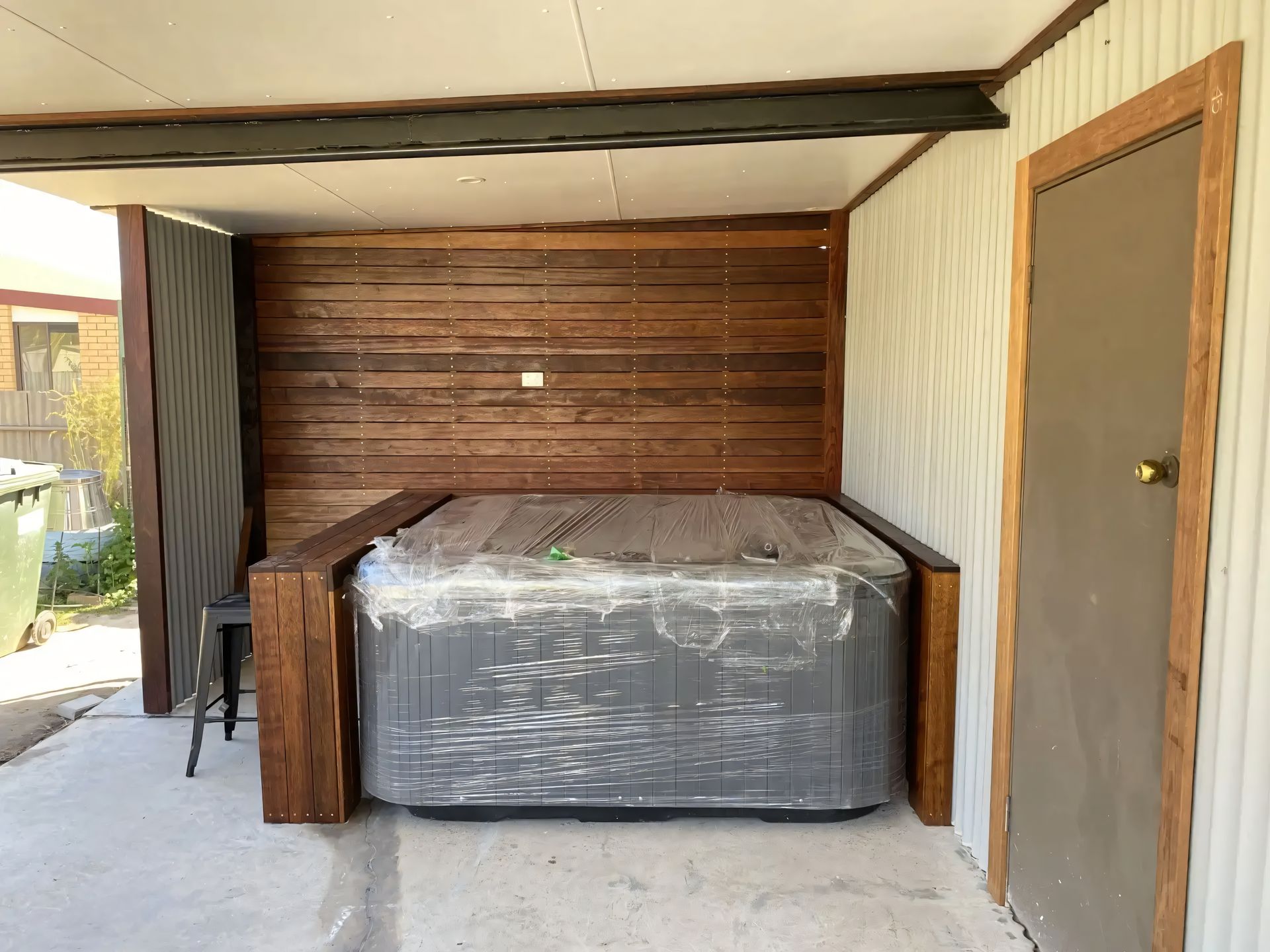 A hot tub is sitting under a wooden structure in a garage. — CBY Carpentry & Renovations In Dubbo, NSW