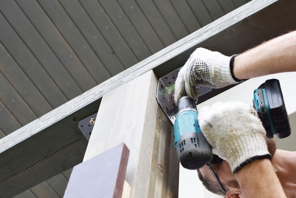 A Man Is Using A Drill On A Piece Of Wood — CBY Carpentry & Renovations In Dubbo, NSW