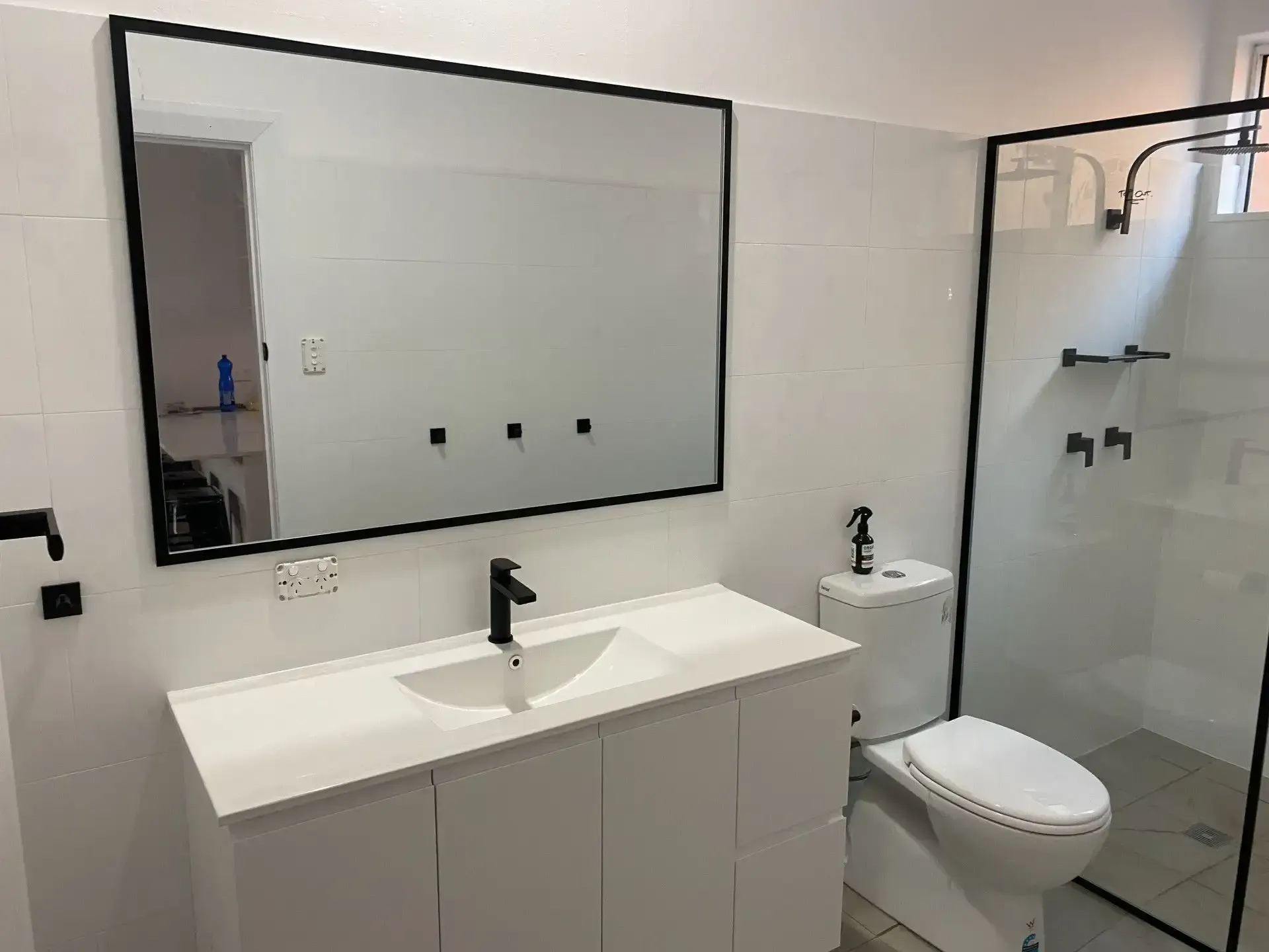 A bathroom with a sink , toilet , shower and mirror. 