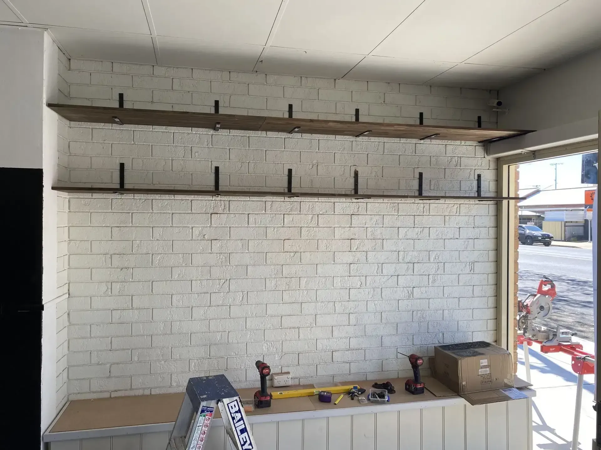 A ladder is sitting on a counter in front of a white brick wall. 