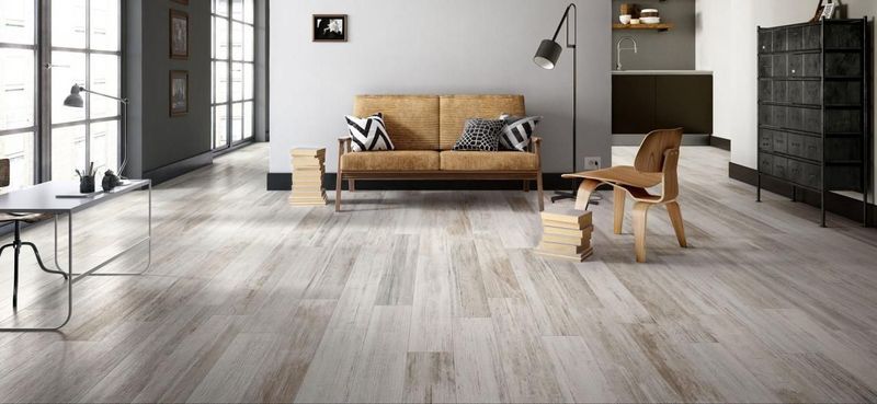 Ampio soggiorno moderno con pavimento in legno, divano marrone chiaro e grandi finestre.