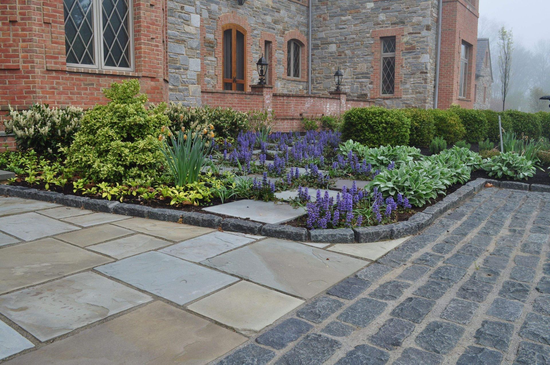 A Garden with Plants and Bushes in Front of a Building — Kennett Square, PA — Classic Lawns