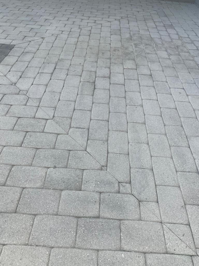 Gray brick pavers on a driveway, with visible cracks in several bricks.