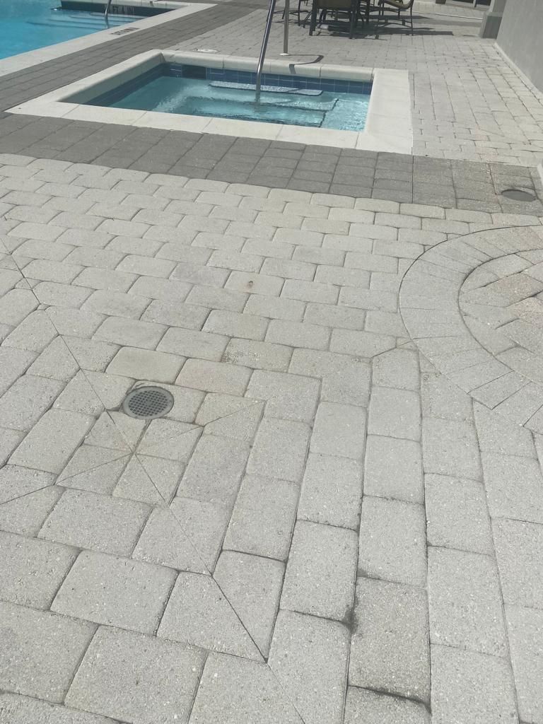 Brick patio with a hot tub and pool in the background.