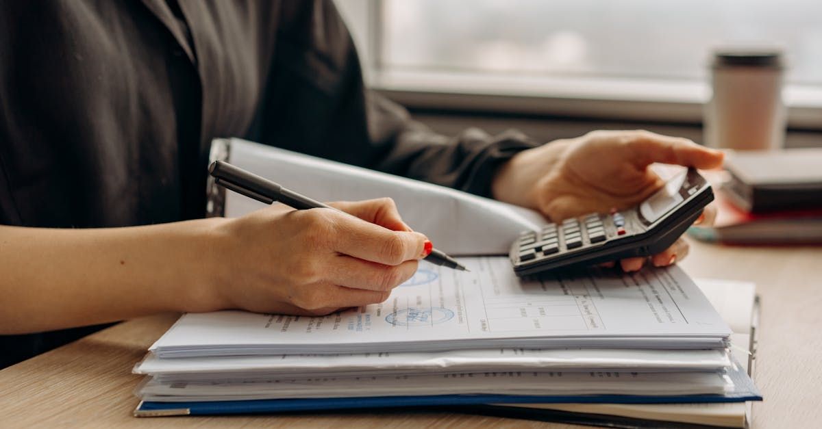 A woman is using a calculator and writing on a piece of paper.