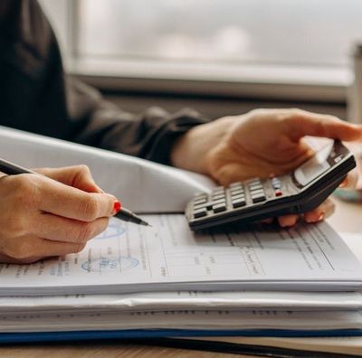 A person is using a calculator and writing on a piece of paper.