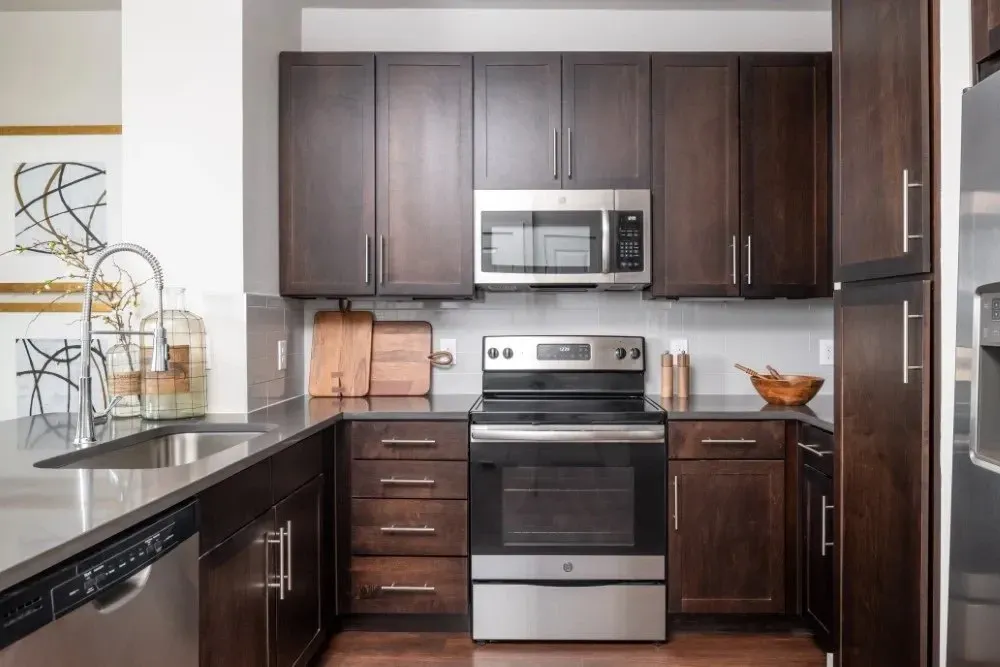 Modern kitchen featuring dark wood cabinets and stainless steel appliances.