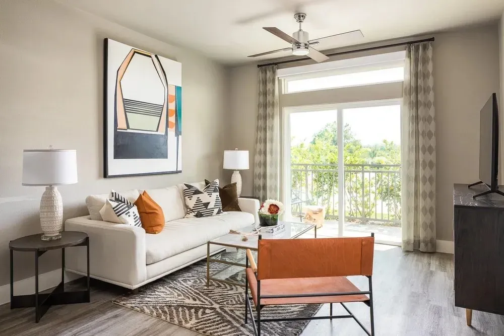 Stylish living room featuring a white sofa, colorful artwork, and balcony access.