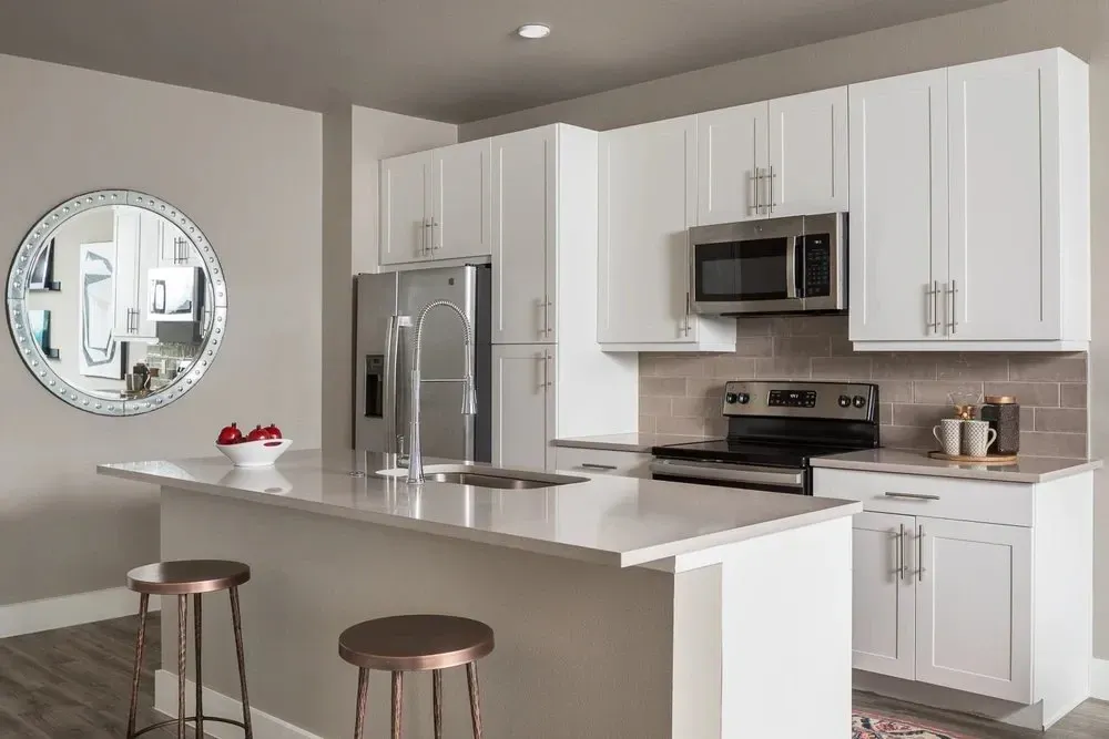 Modern kitchen with white cabinets, stainless steel appliances, and a circular mirror