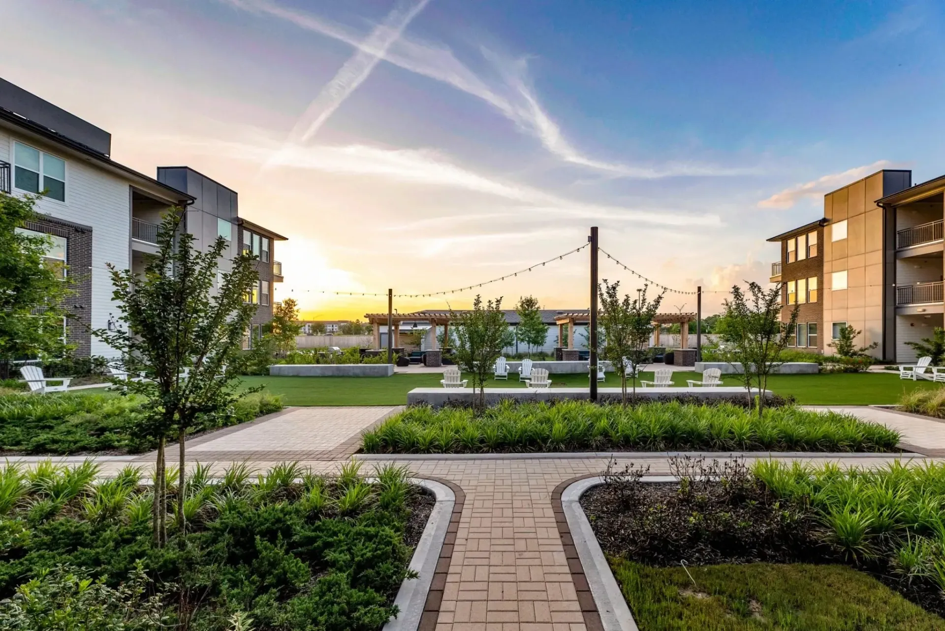 Beautiful landscaped community area with seating and pathways at sunset.