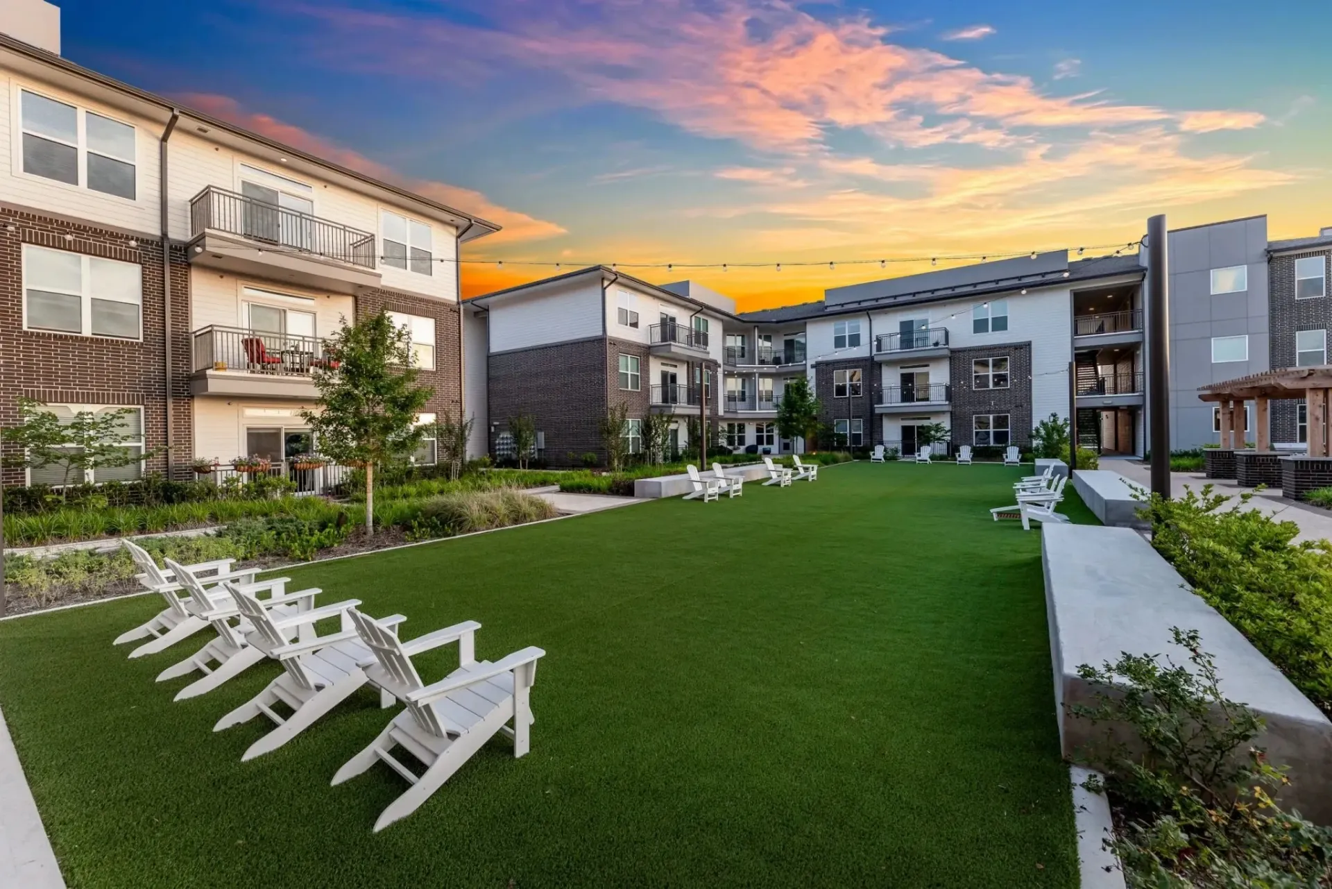 Outdoor communal area with white chairs and apartment buildings in the background