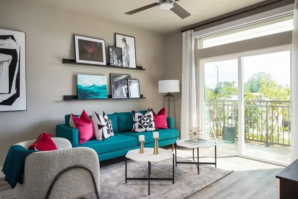 Stylishly furnished living room with a teal couch and large windows