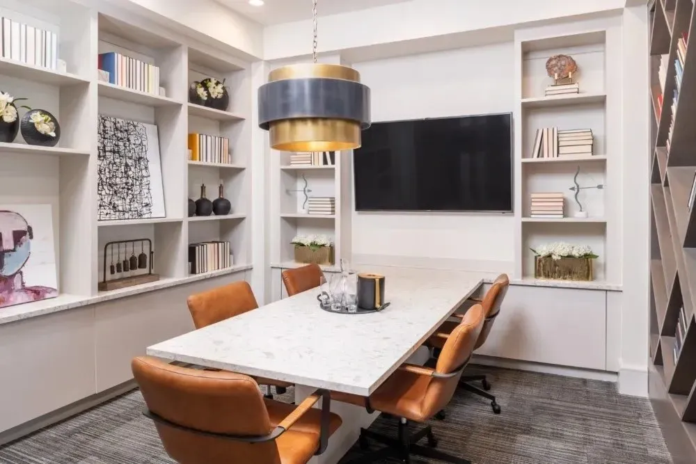 Modern shared space with a large table, chairs, and a wall-mounted TV.