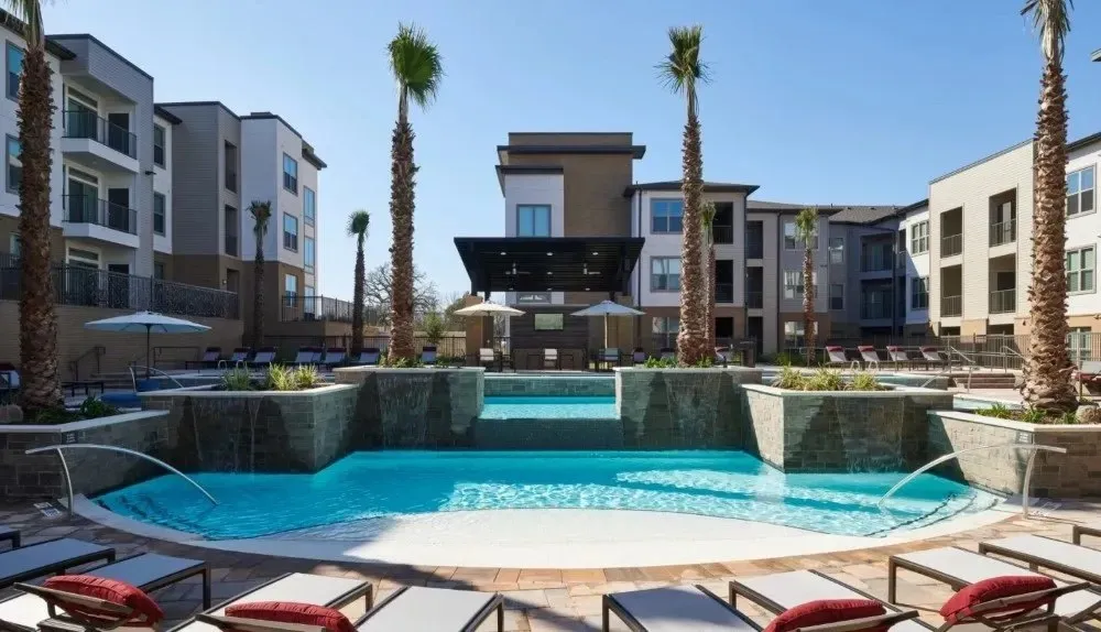 Resort-style pool area with lounge chairs and palm trees.
