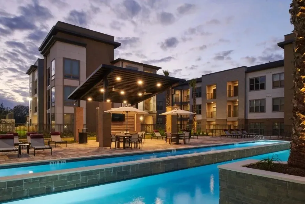 Pool area with lounge chairs and umbrellas near apartment buildings