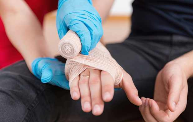 A person is getting a bandage on their hand.