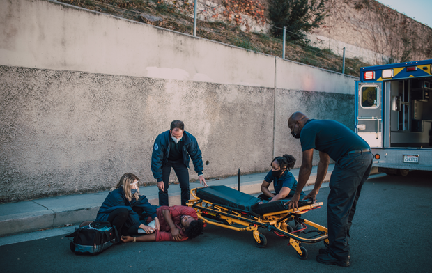 A group of paramedics are helping a woman on a stretcher.