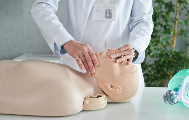 A doctor is putting an oxygen mask on a mannequin.