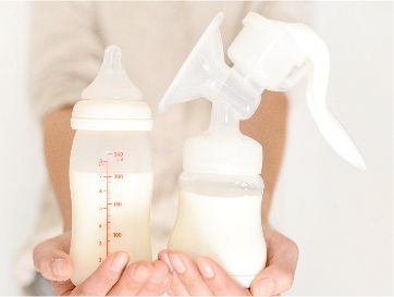 一名婦女拿著兩瓶牛奶和一個吸乳器。