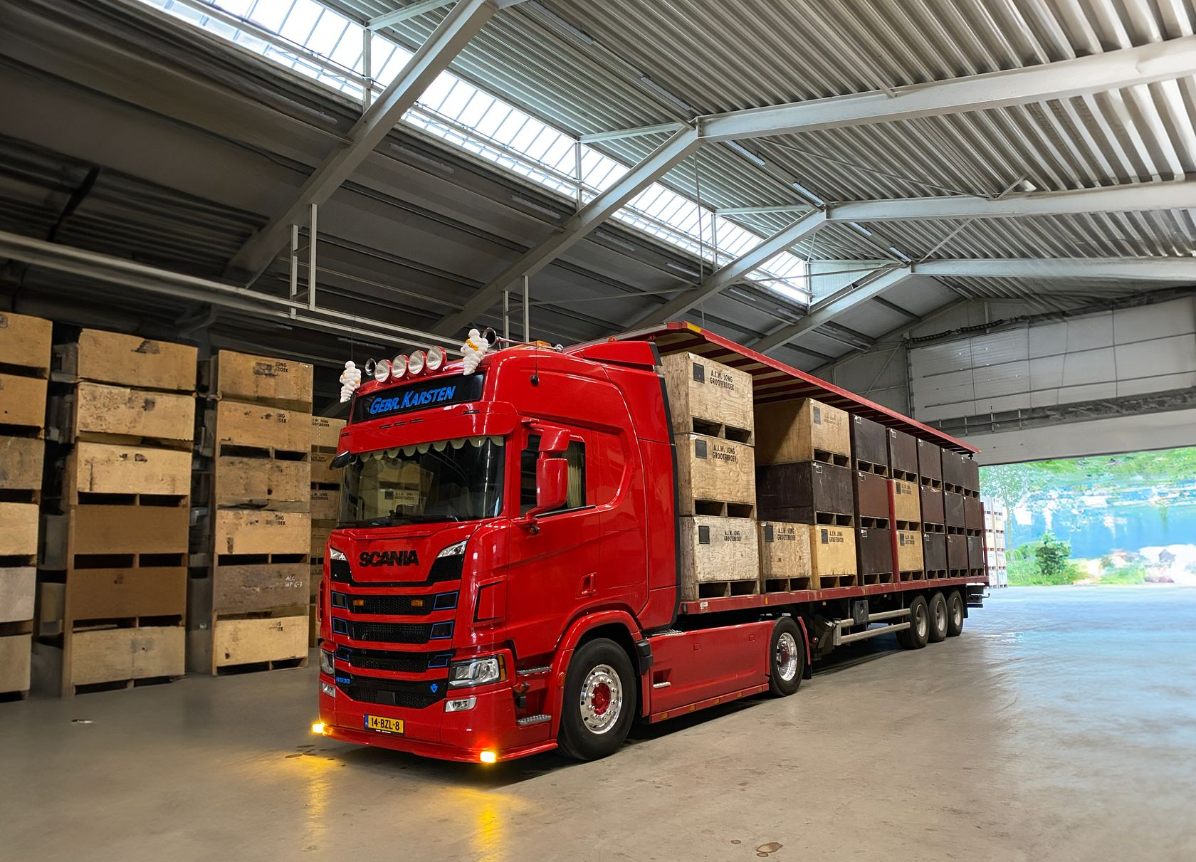 Rode Scania-vrachtwagen geladen met dozen in een loods.