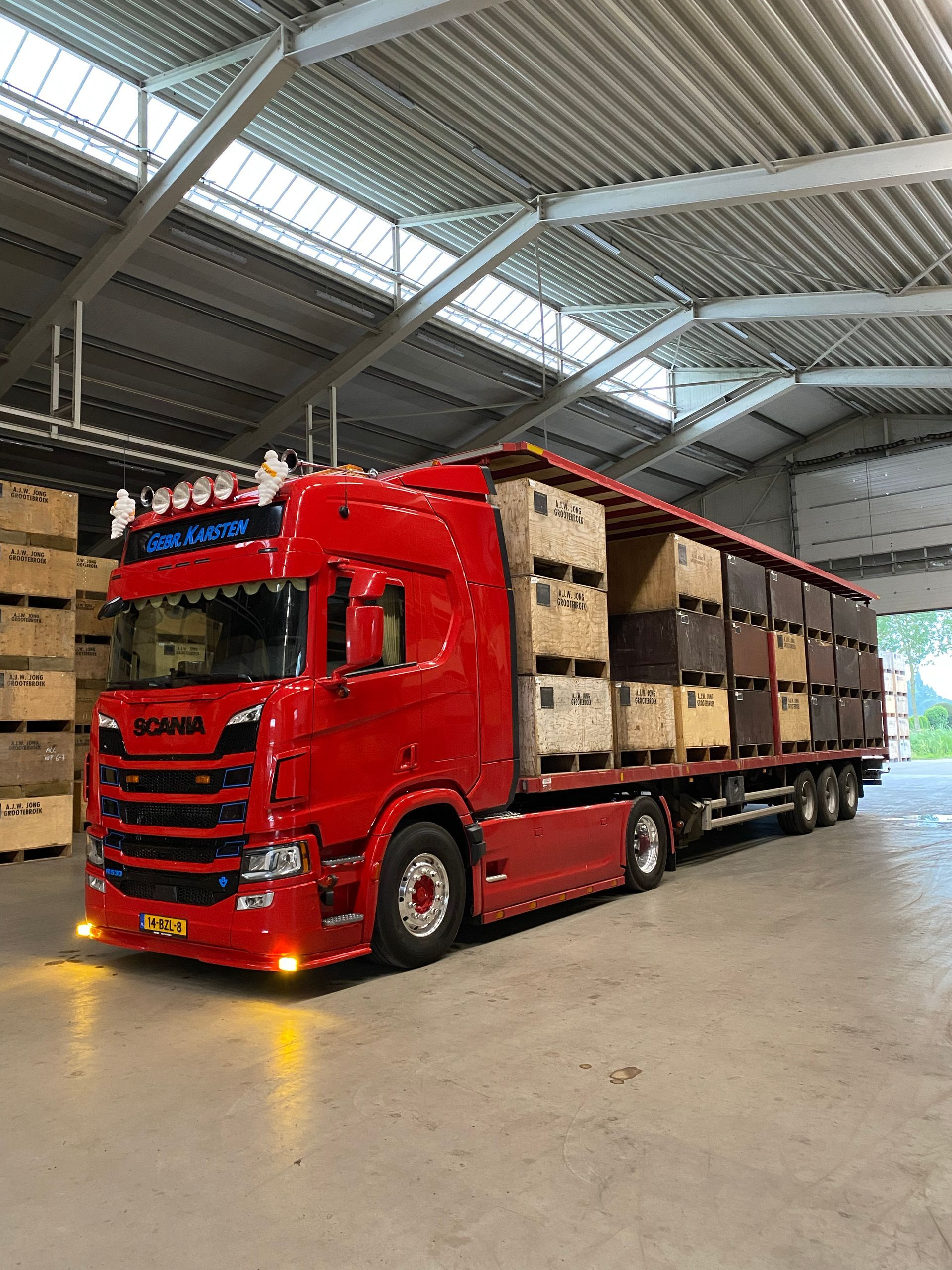 Rode Scania-vrachtwagen geladen met kratten in een loods.