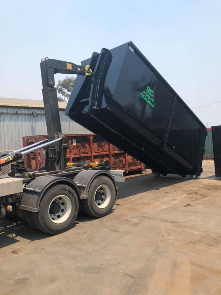 A Dumpster Is Being Loaded Onto A Truck In A Parking Lot — RiverCity Recyclers In Taree, NSW