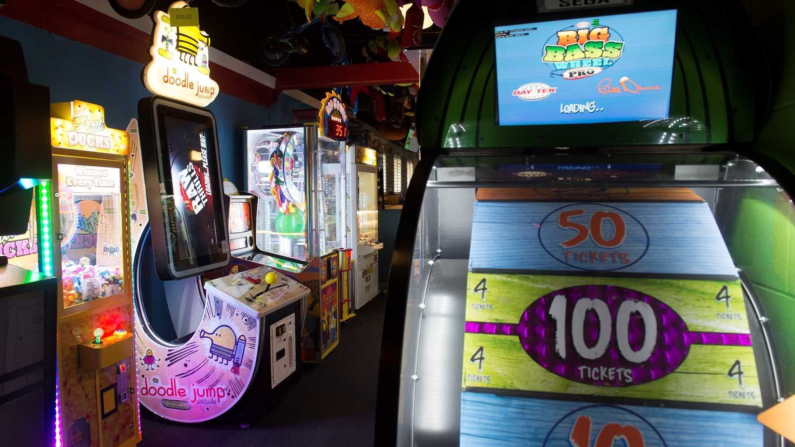 A bunch of arcade games are lined up in a room.