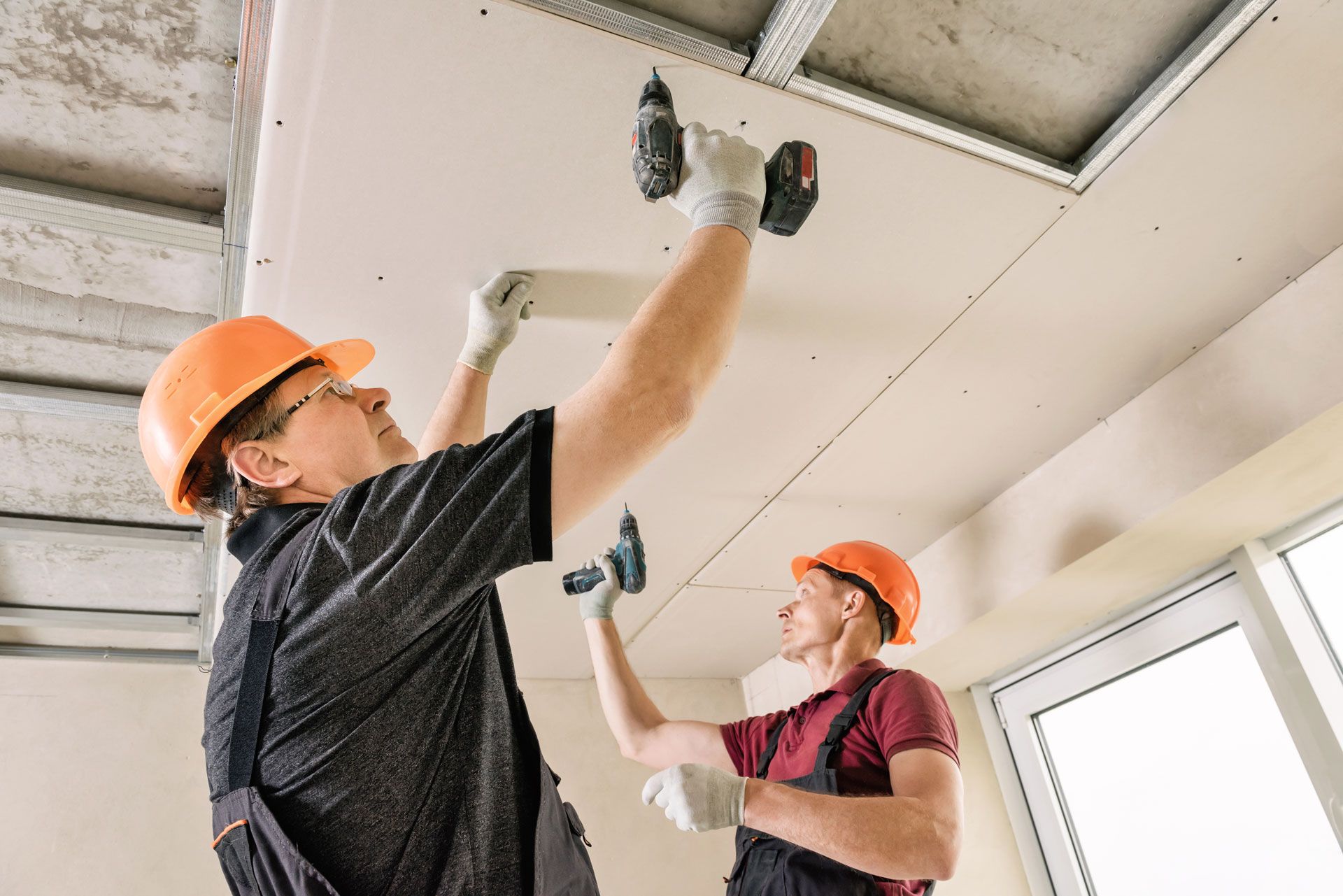 two men are working on a ceiling in a room